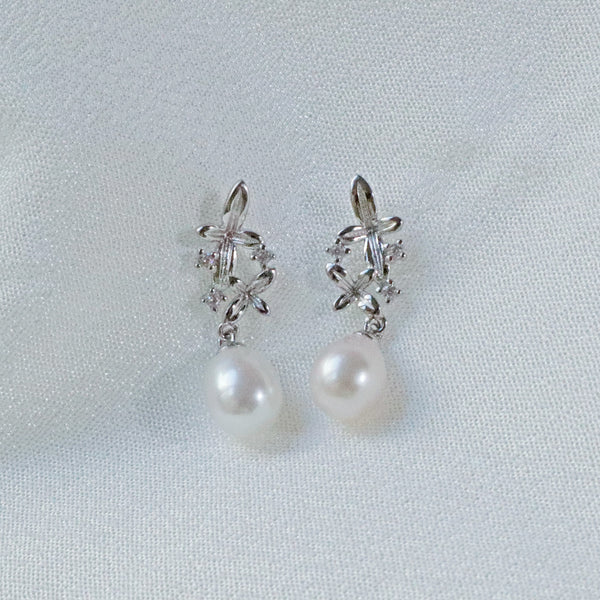 Pearlpals A pair of silver earrings with small flower designs, sparkling zircon stones, and a dangling freshwater pearl.