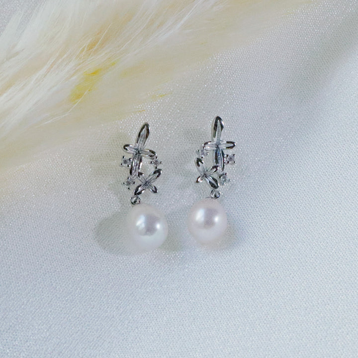 Pearlpals A pair of silver earrings with small flower designs, sparkling zircon stones, and a dangling freshwater pearl.