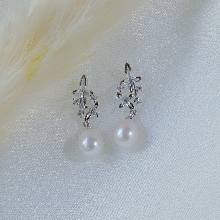 Pearlpals A pair of silver earrings with small flower designs, sparkling zircon stones, and a dangling freshwater pearl.