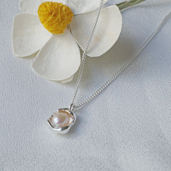 Pearlpals pearl pendant necklace features a half-concealed pearl nestled within an egg-shaped pendant, crafted from sterling silver.