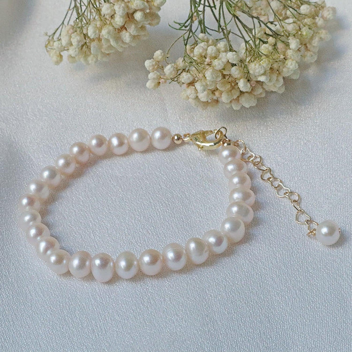 Pearlpals A gold-plated pearl bracelet with a simple design, heart-shaped chain, and a single pearl charm at the end