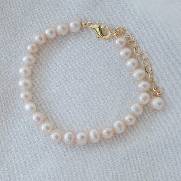 Pearlpals A gold-plated pearl bracelet with a simple design, heart-shaped chain, and a single pearl charm at the end