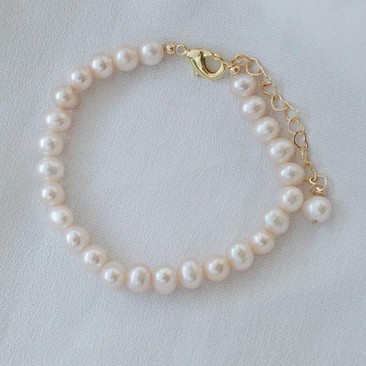 Pearlpals A gold-plated pearl bracelet with a simple design, heart-shaped chain, and a single pearl charm at the end