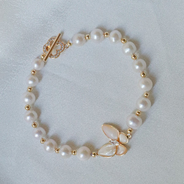 Pearlpals A gold-plated bracelet with pearls and gold beads, featuring a butterfly charm made of petal-shaped pearls