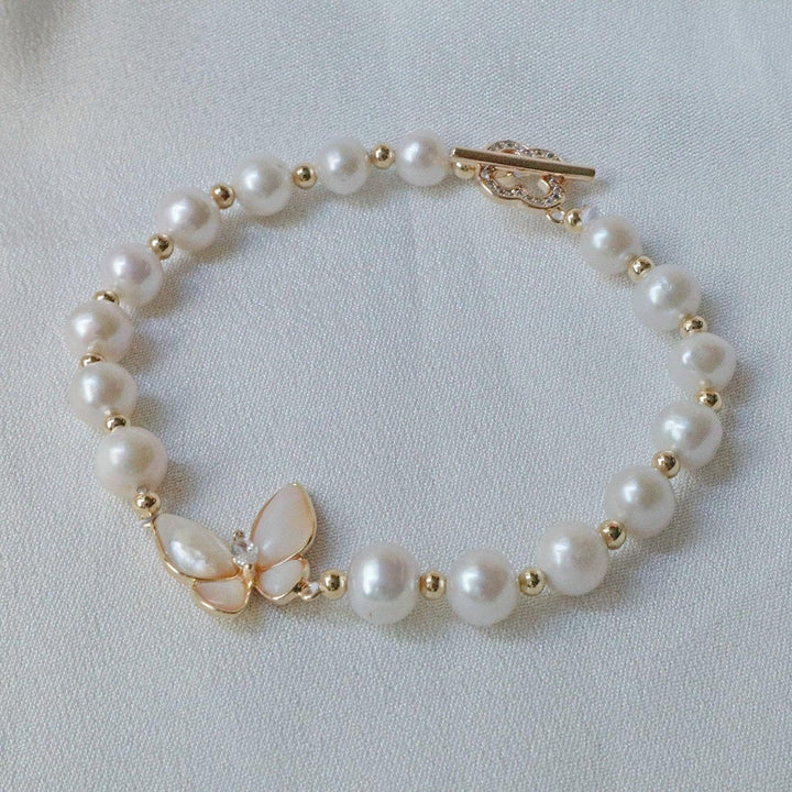 Pearlpals A gold-plated bracelet with pearls and gold beads, featuring a butterfly charm made of petal-shaped pearls