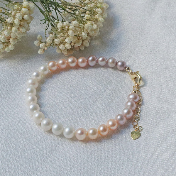 Pearlpals A gold-plated bracelet with gradient pearls transitioning from white to purple, displayed on a soft white fabric background.