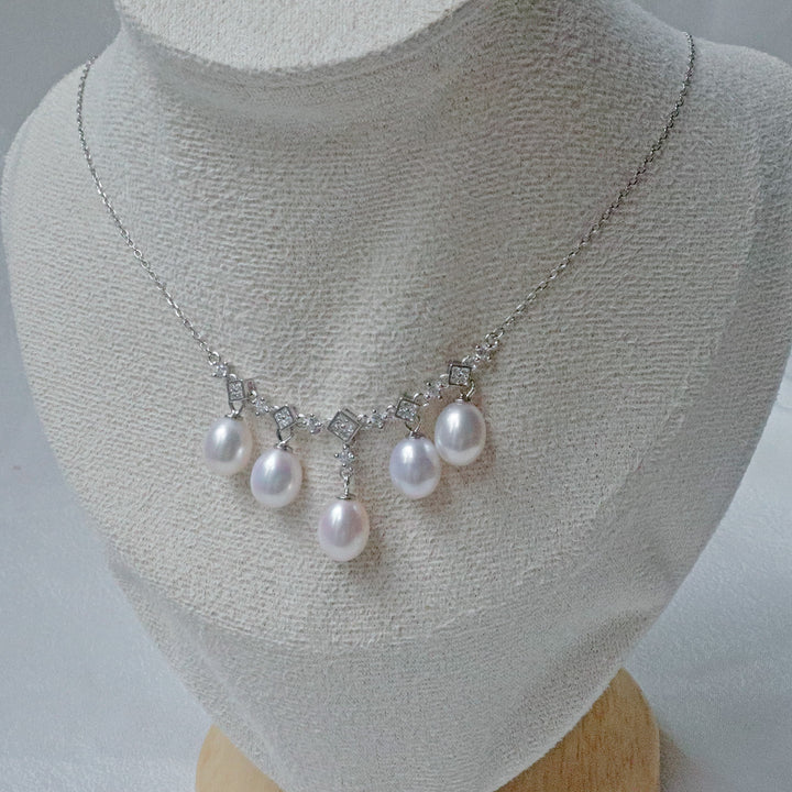 A sterling silver necklace featuring 8mm teardrop pearls and sparkling accents