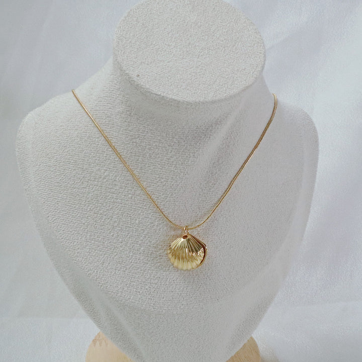 Gold-plated necklace with a shell-shaped pendant and a pearl inside, hanging on a gold chain